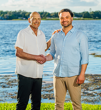 Two healthcare professionals shaking hands by a waterfront, representing collaboration in pain management at West Florida Pain Management.